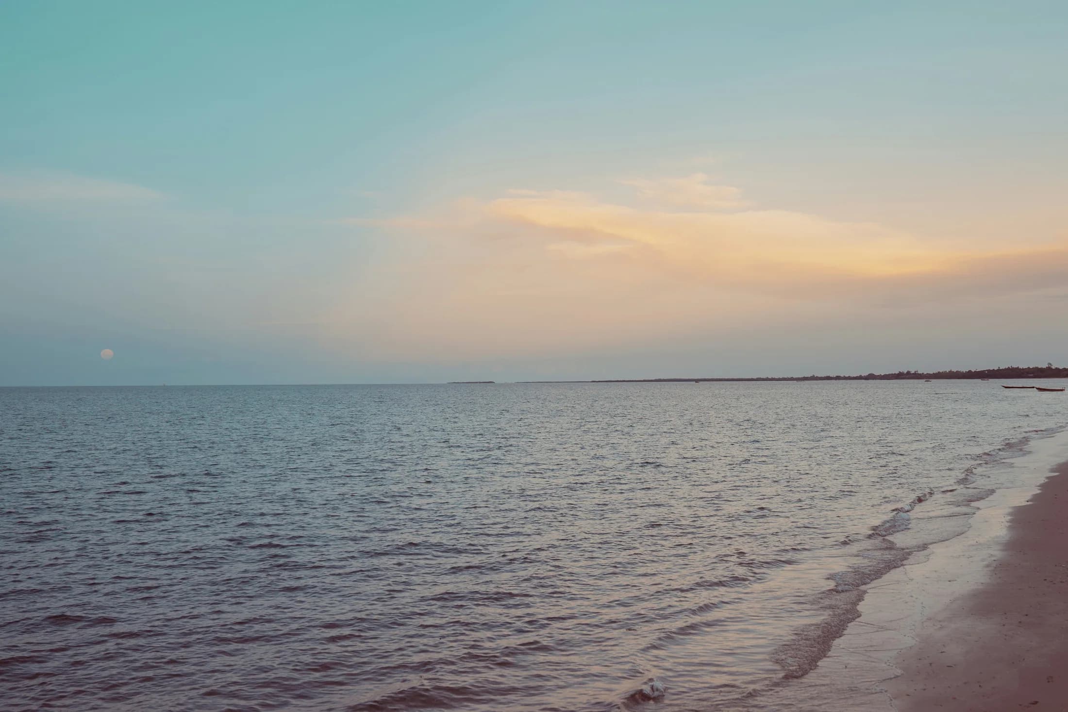 Gentle waves along the Bagamoyo shoreline beneath a pastel evening sky