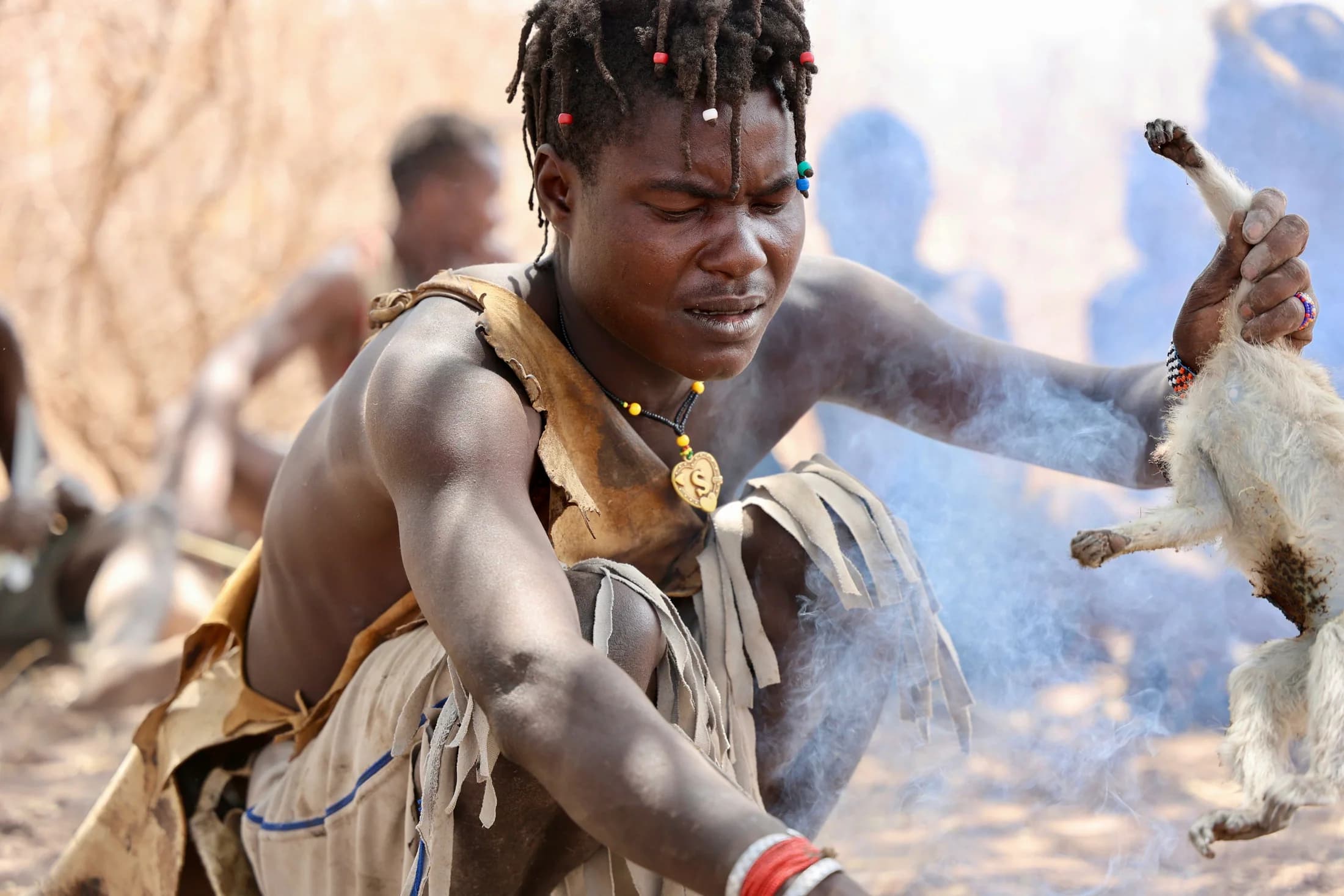 A Hadzabe man singeing a hunted animal over a fire in Tanzania